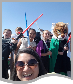 Teacher poses with students dressed as Star Wars characters and tigers with lightsabers