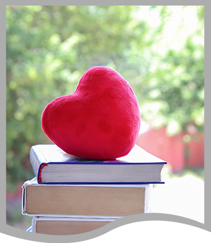 Plush red heart on top of books in front of trees